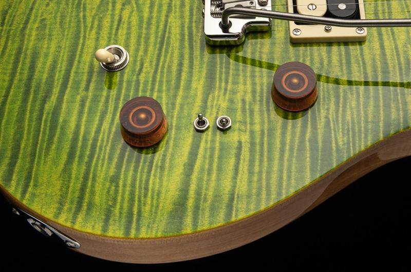 Electric guitar body with a vivid green and yellow flamed wood pattern, two brown knobs, toggle switches, and chrome hardware.