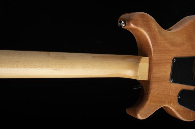 Light wood electric guitar neck joins a natural finish body, with black plates and metal screws visible on the back against a black background.