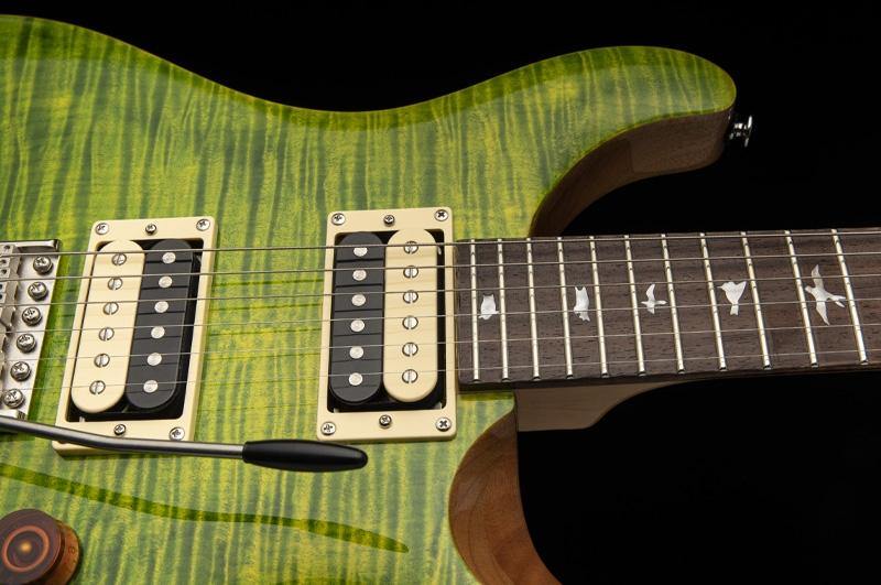 Green electric guitar with a wood grain pattern, two cream-outlined humbucker pickups, tremolo arm, and fretboard featuring bird-shaped inlays.
