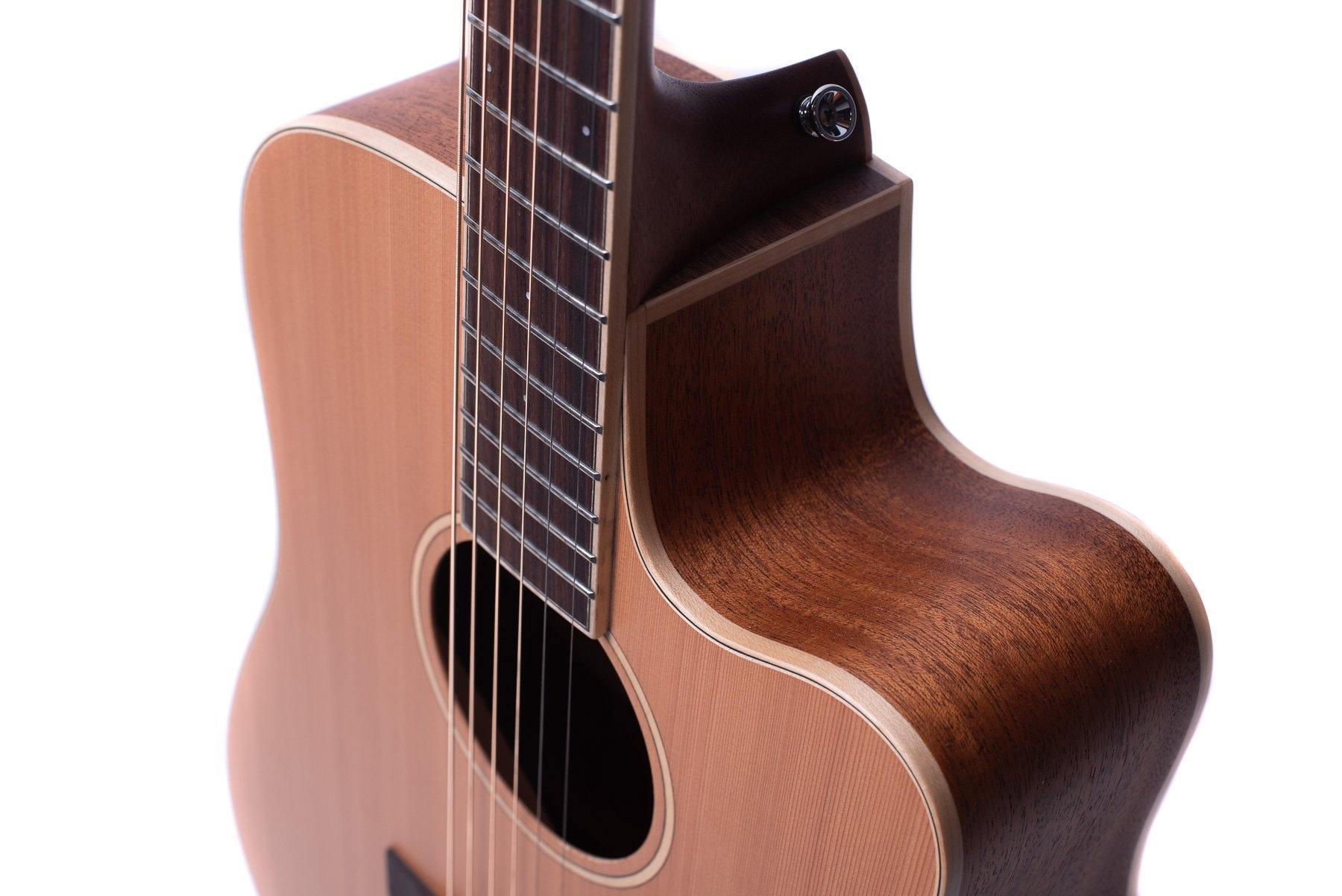 Close-up of a wooden acoustic guitar showing the strings, fretboard, soundhole, and a cutaway body for easier access to higher frets.
